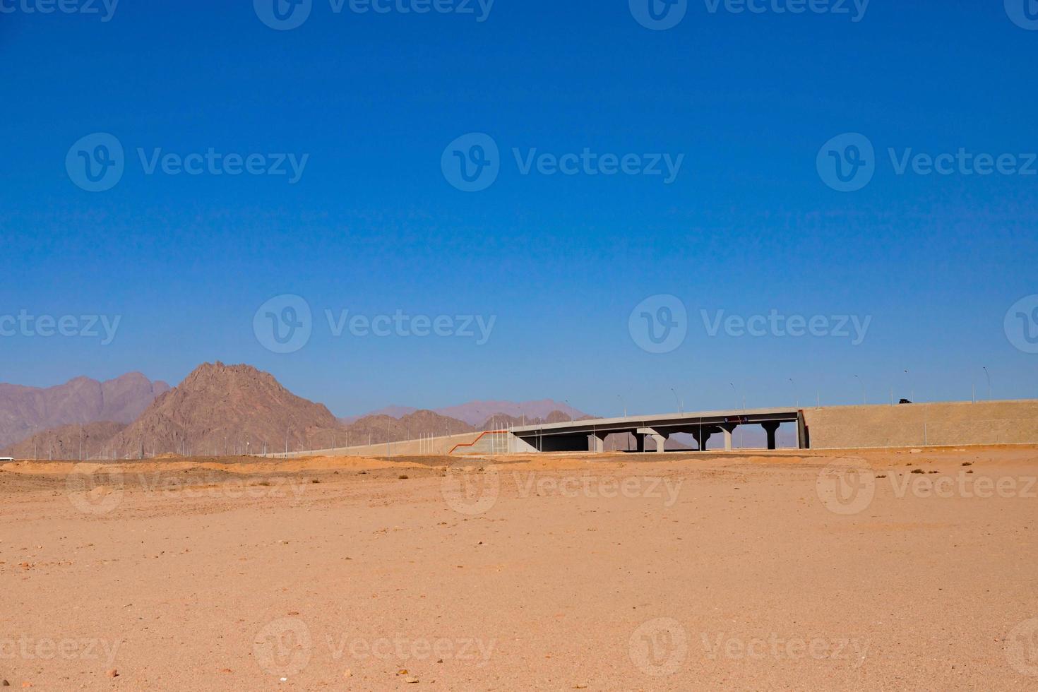 A road with a bridge through the desert. photo