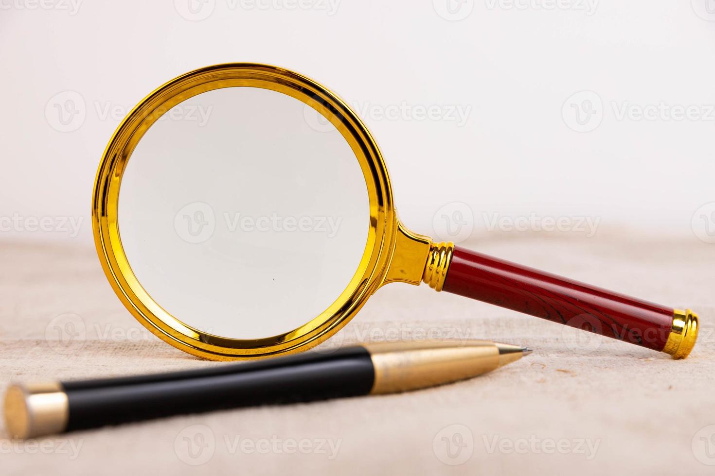 Magnifying glass of gold color, pen on a light background and linen fabric. A copy of the space. photo