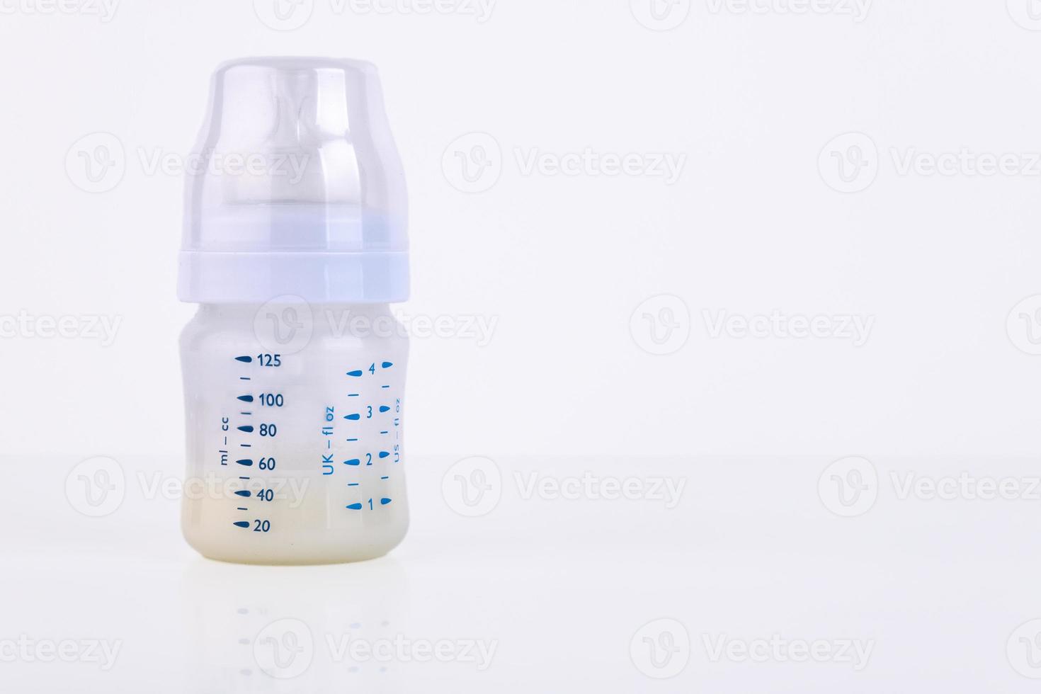 Baby bottle with pacifier and milk for feeding milk on a light background. Copy space. photo