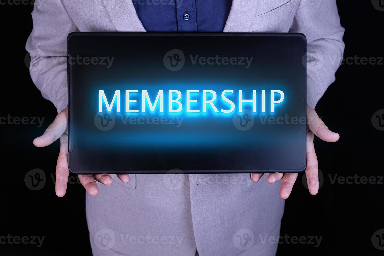 MEMBERSHIP word, text written in neon letters on a laptop which is being held by a businessman in a gray suit. photo