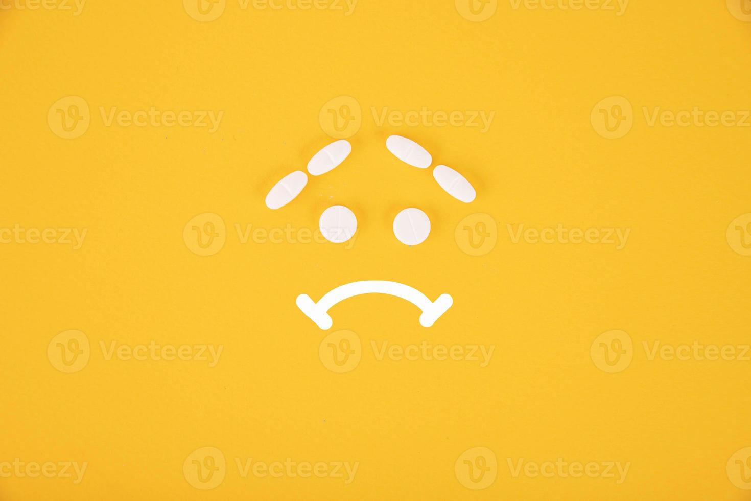 The pills are stacked in the form of a sad smiley on a yellow background. Copyspace photo