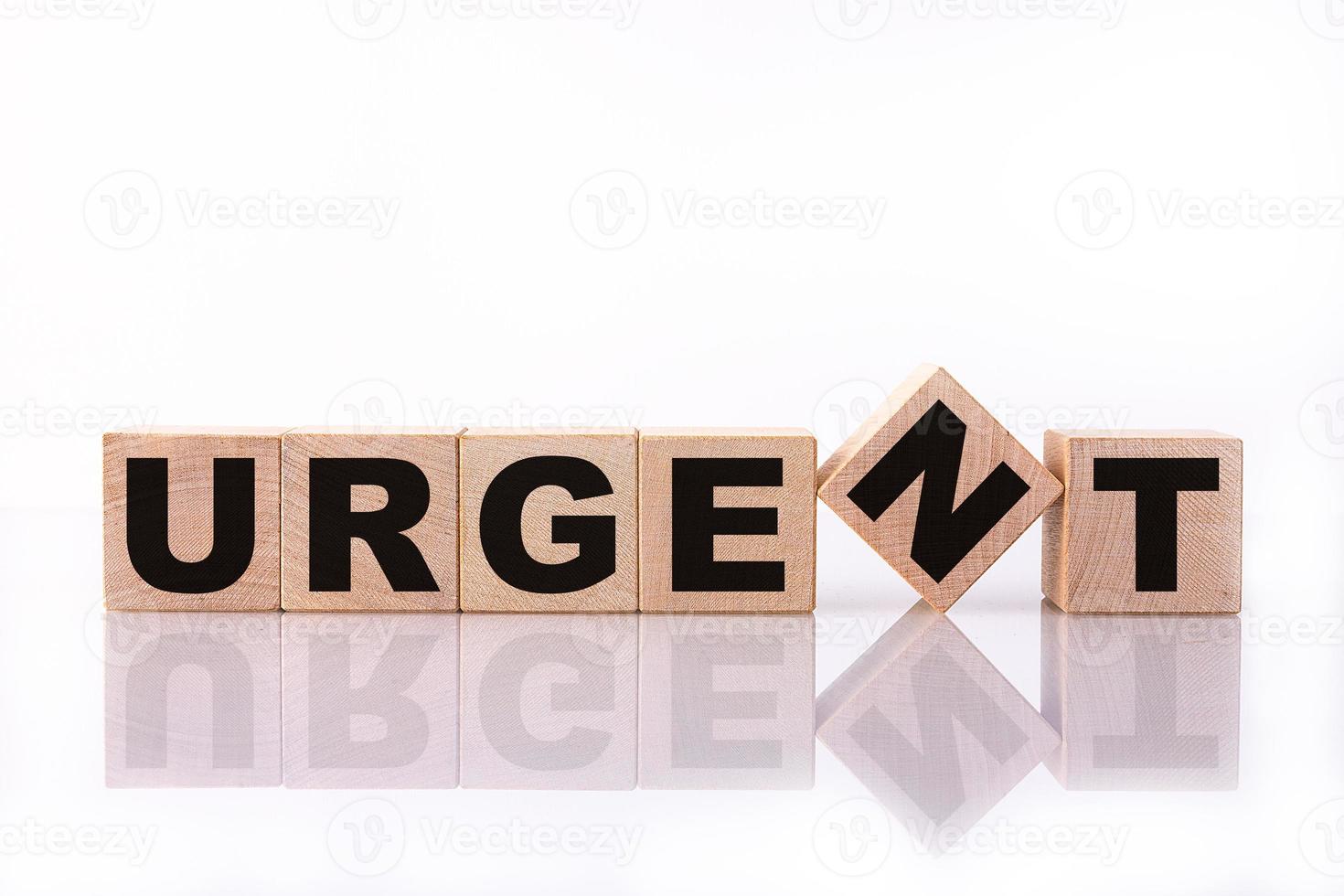 URGENT word, text, written on wooden cubes, building blocks, over white background with reflection. photo