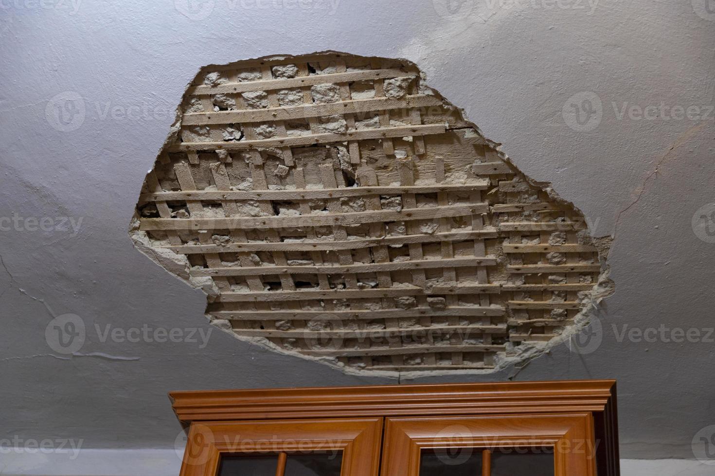 Collapsed plaster from the white ceiling in the interior of an old house. photo