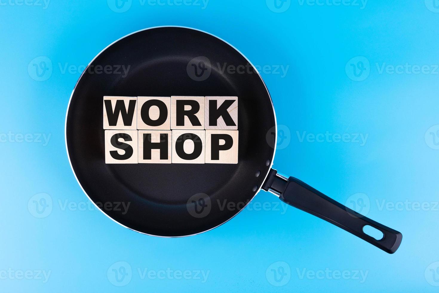 WORKSHOP word, text written on wooden cubes, building blocks lying in a frying pan, and blue background. photo