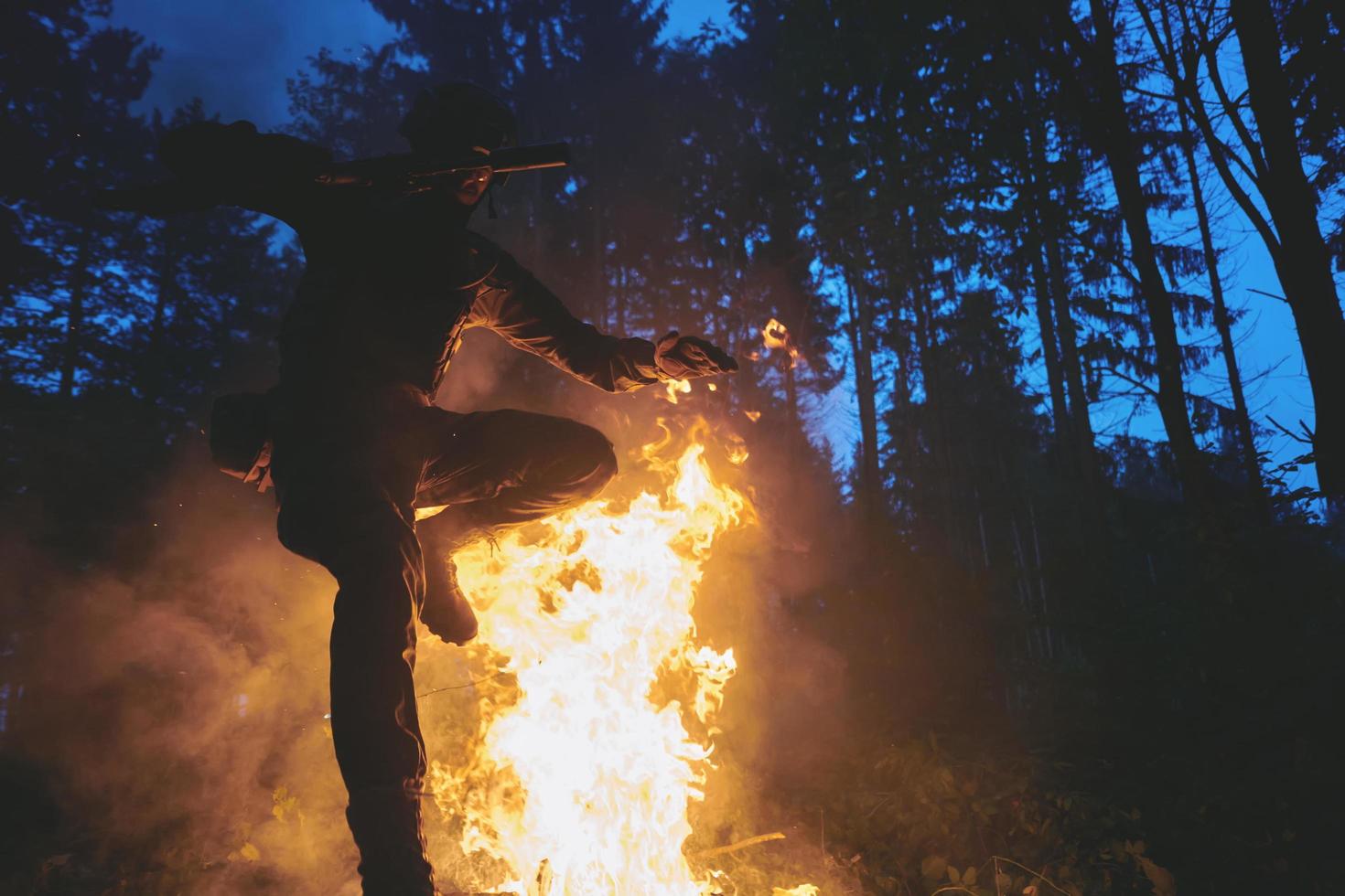 Soldier in Action at Night jumping over fire photo