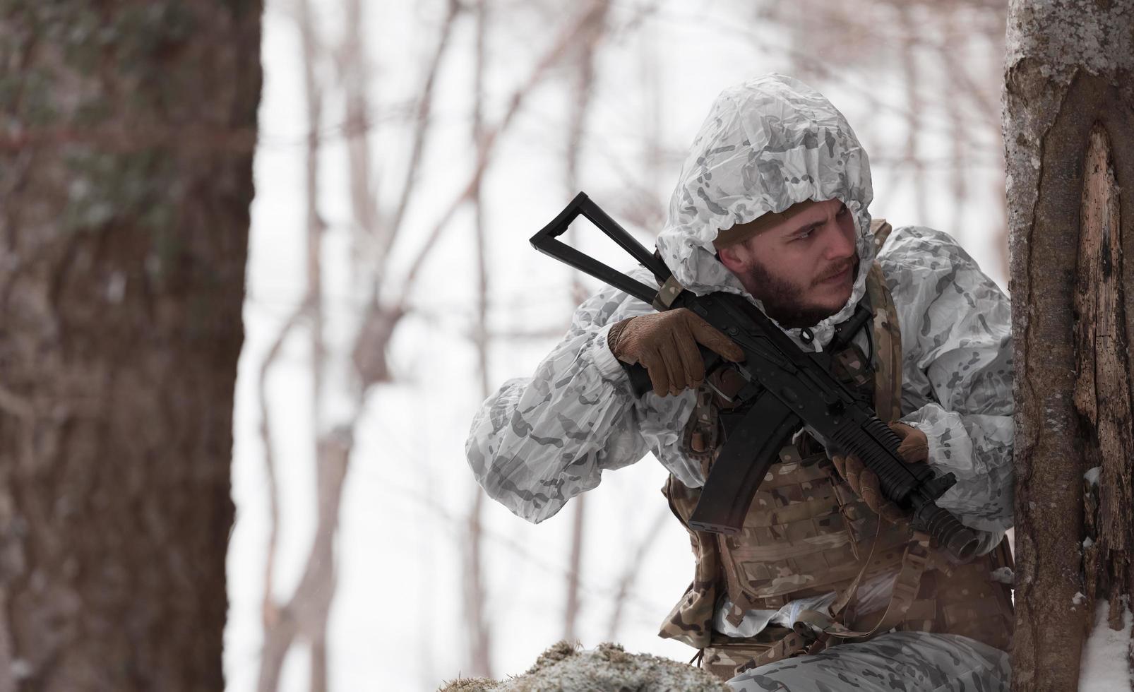 Winter war in the Arctic mountains. Operation in cold conditions.Soldier in winter camouflaged uniform in Modern warfare army on a snow day on forest battlefield with a rifle. Selective focus photo