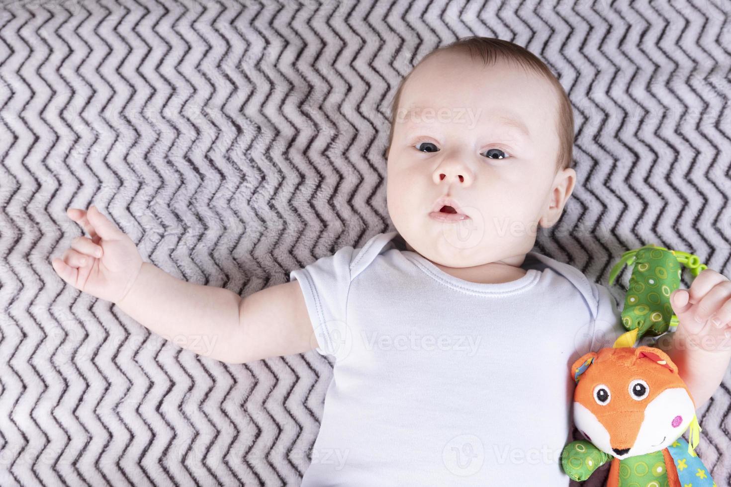 Cute baby boy playing with a colored toy. Copy space. photo