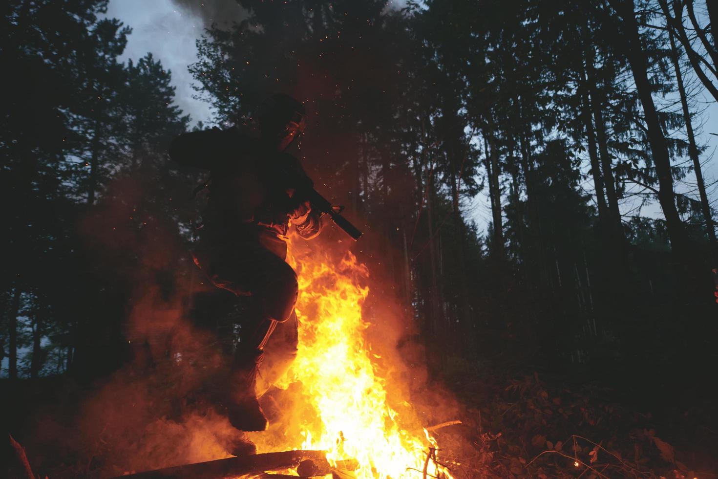 Soldier in Action at Night jumping over fire photo