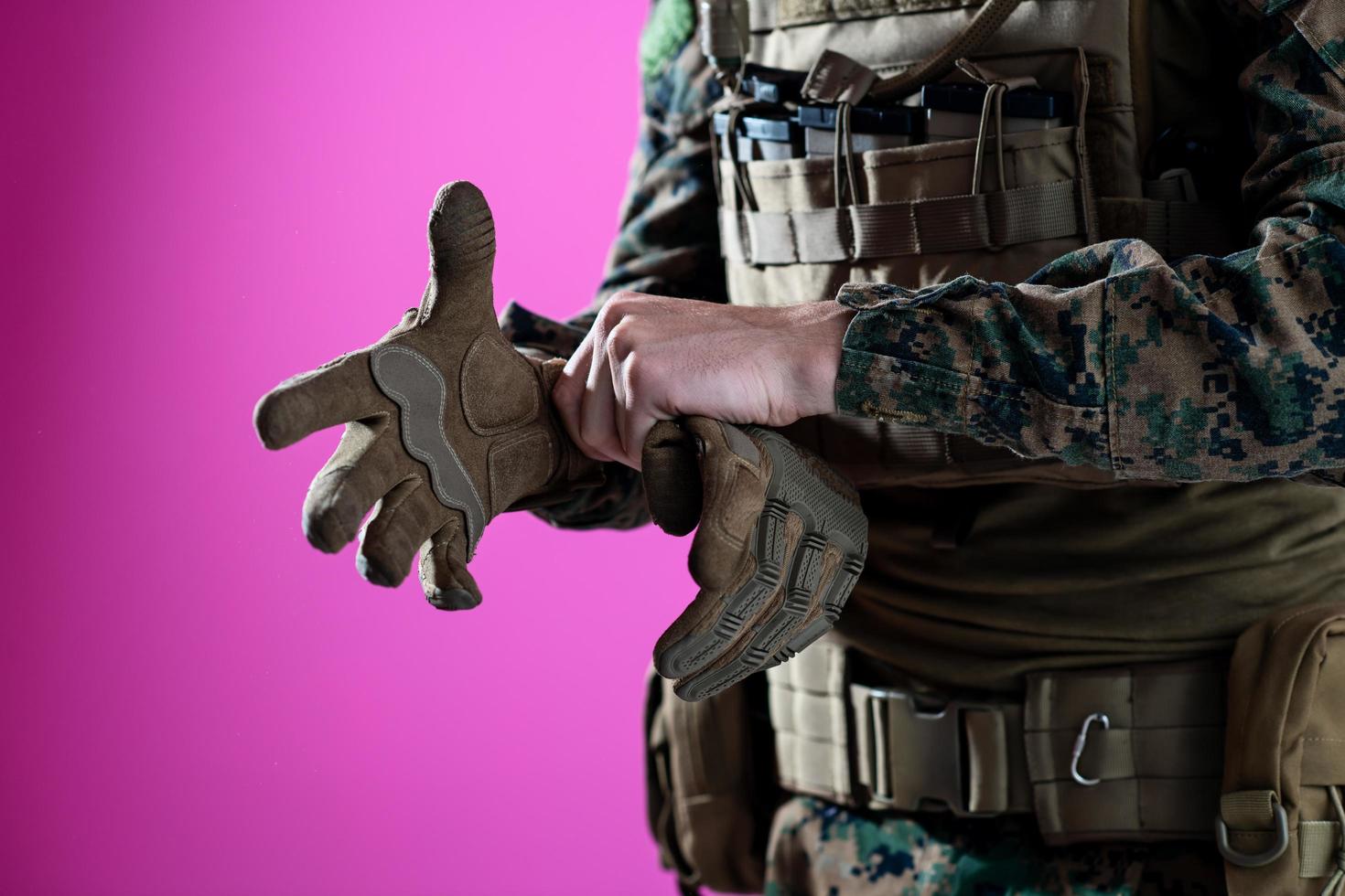 closeup of soldier hands putting protective battle gloves pink background photo