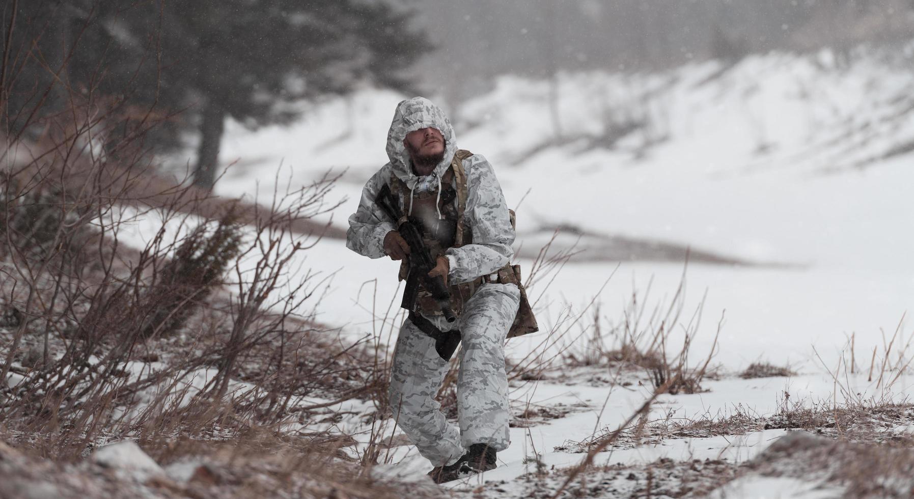 guerra de invierno en las montañas árticas. operación en condiciones frías. soldado en uniforme camuflado de invierno en el ejército de guerra moderno en un día de nieve en el campo de batalla del bosque con un rifle. enfoque selectivo foto