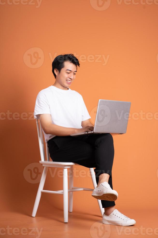 man sitting on chair  isolated on orange background photo