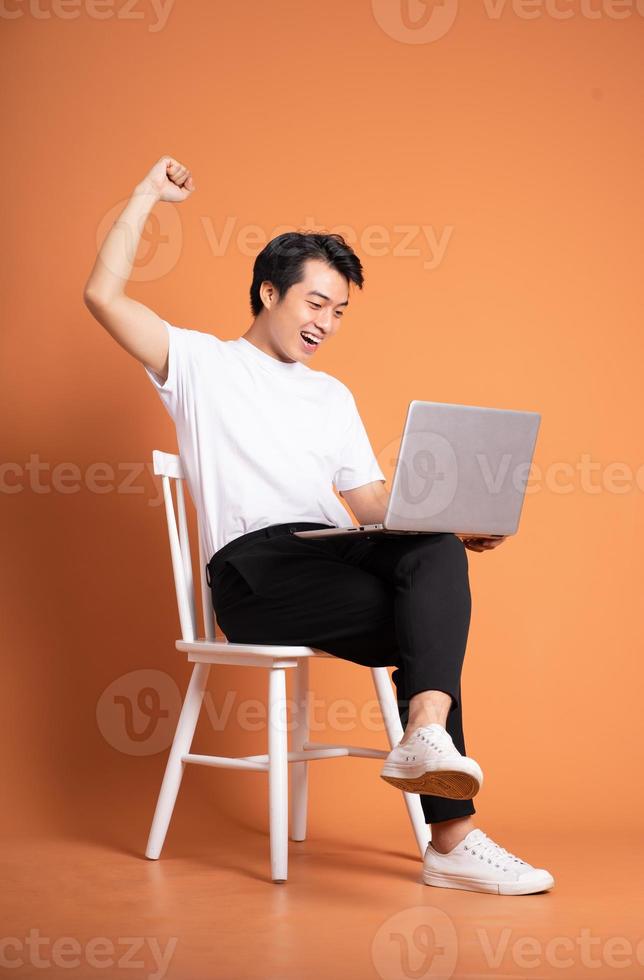 man sitting on chair  isolated on orange background photo