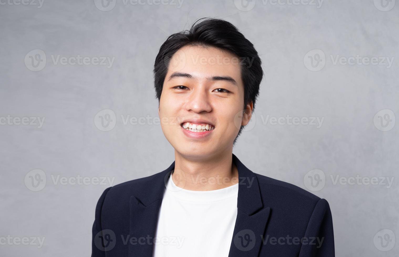 Young business man wearing a suit posing on a grey background photo