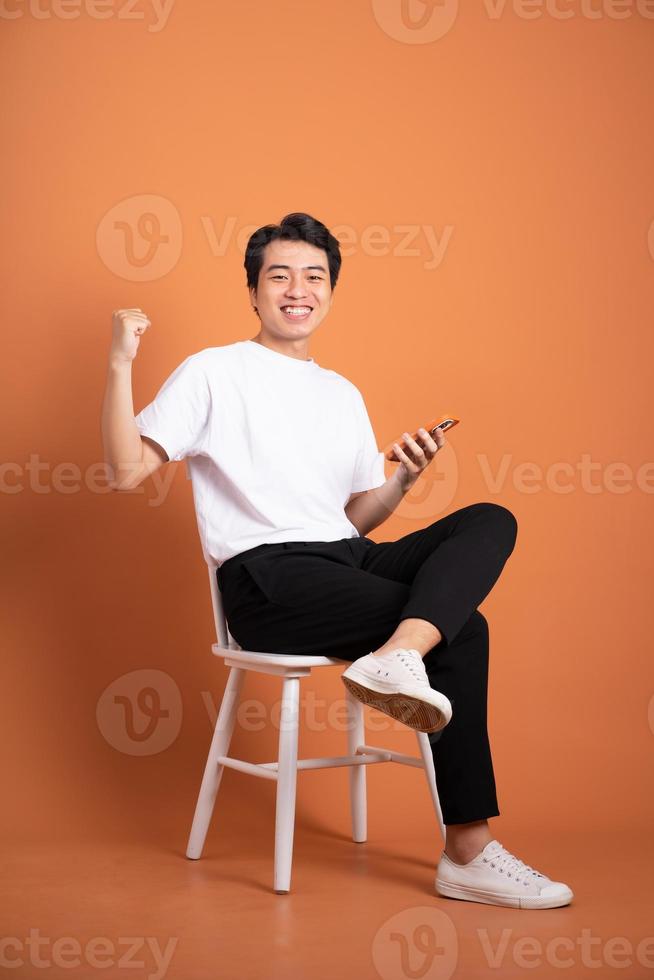 man sitting on chair  isolated on orange background photo
