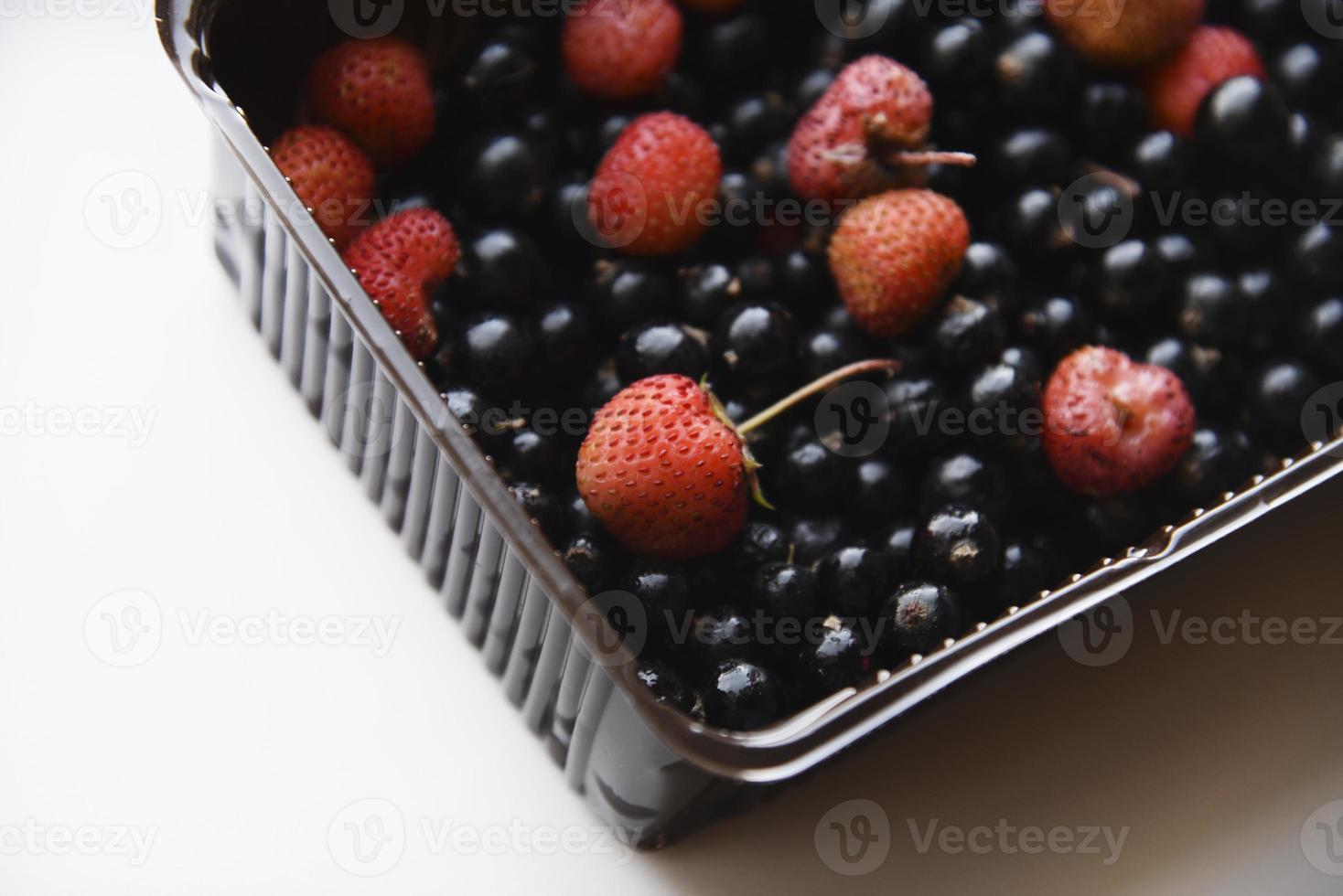 Strawberries and black currants in plastic containers. Delicious fresh berries in a box on a white background. photo