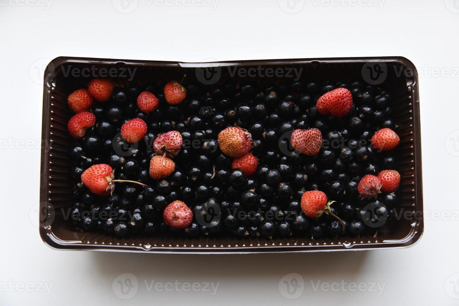 Strawberries and black currants in plastic containers. Delicious fresh berries in a box on a white background. photo