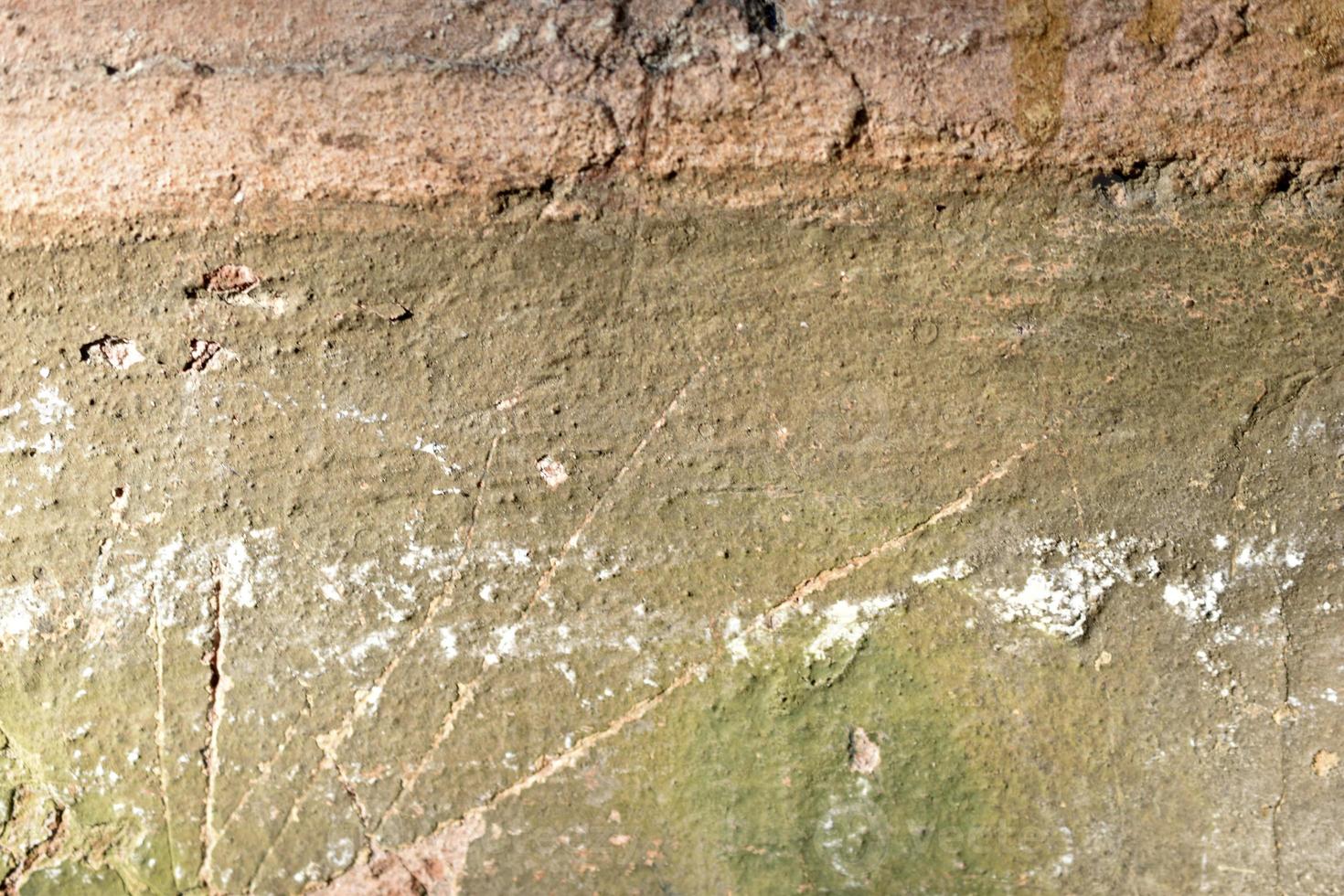 A green broken plastered wall with holes and cracks. photo