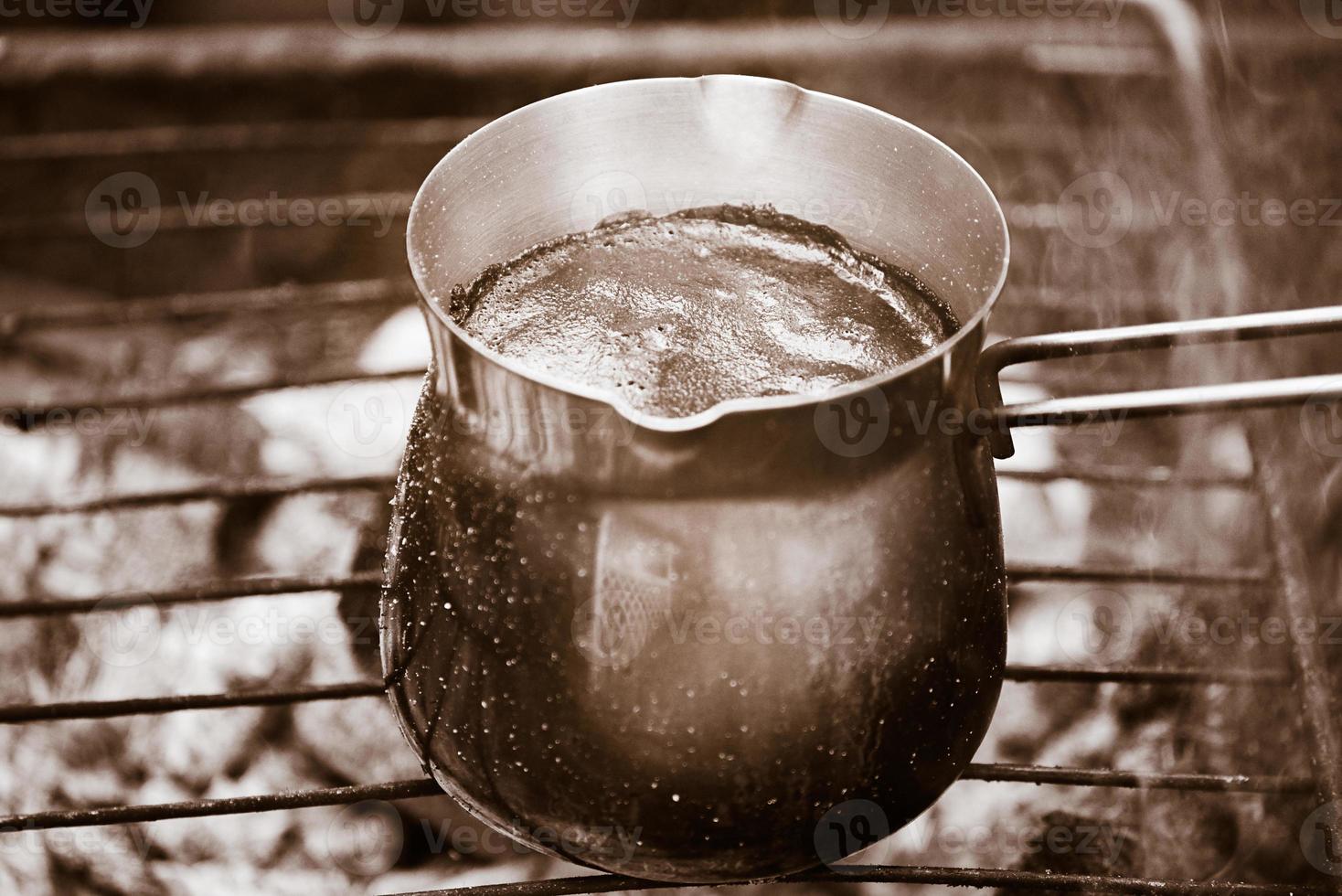 Natural, freshly roasted coffee is prepared in a metal Turk over a fire. Hot coffee with foam. photo