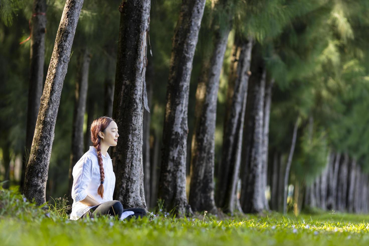 mujer relajadamente practicando la meditación en el bosque de pinos para alcanzar la felicidad de la sabiduría de la paz interior para un concepto sano de la mente y el alma foto