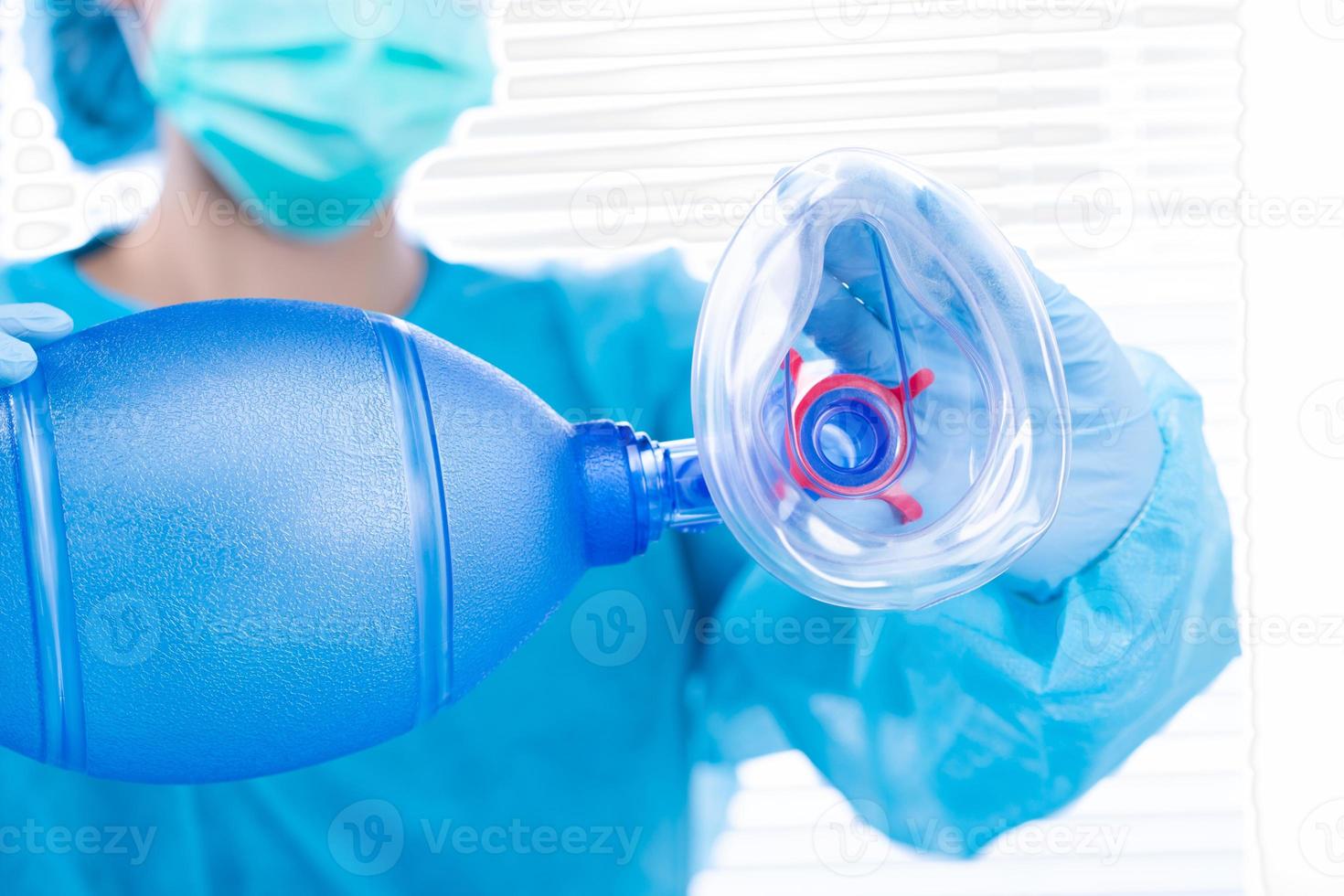 Nurse Doctor hold Oxygen Mask manual pump to camera. Surgeon medical doctor put oxygen mask to patient respiratory breathing before surgical operation with blue uniform, copy space photo