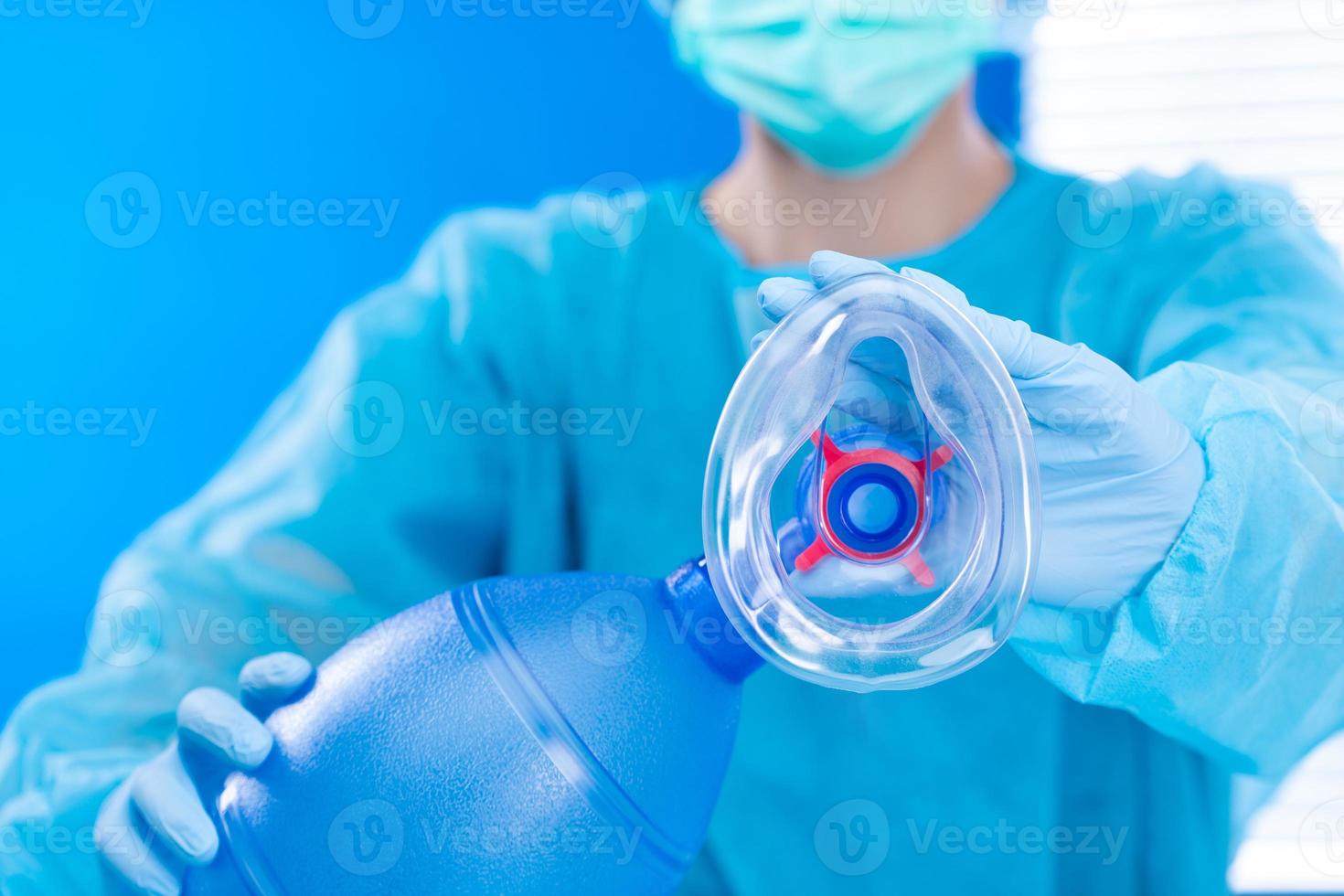 Nurse Doctor hold Oxygen Mask manual pump to camera. Surgeon medical doctor put oxygen mask to patient respiratory breathing before surgical operation with blue uniform, copy space photo