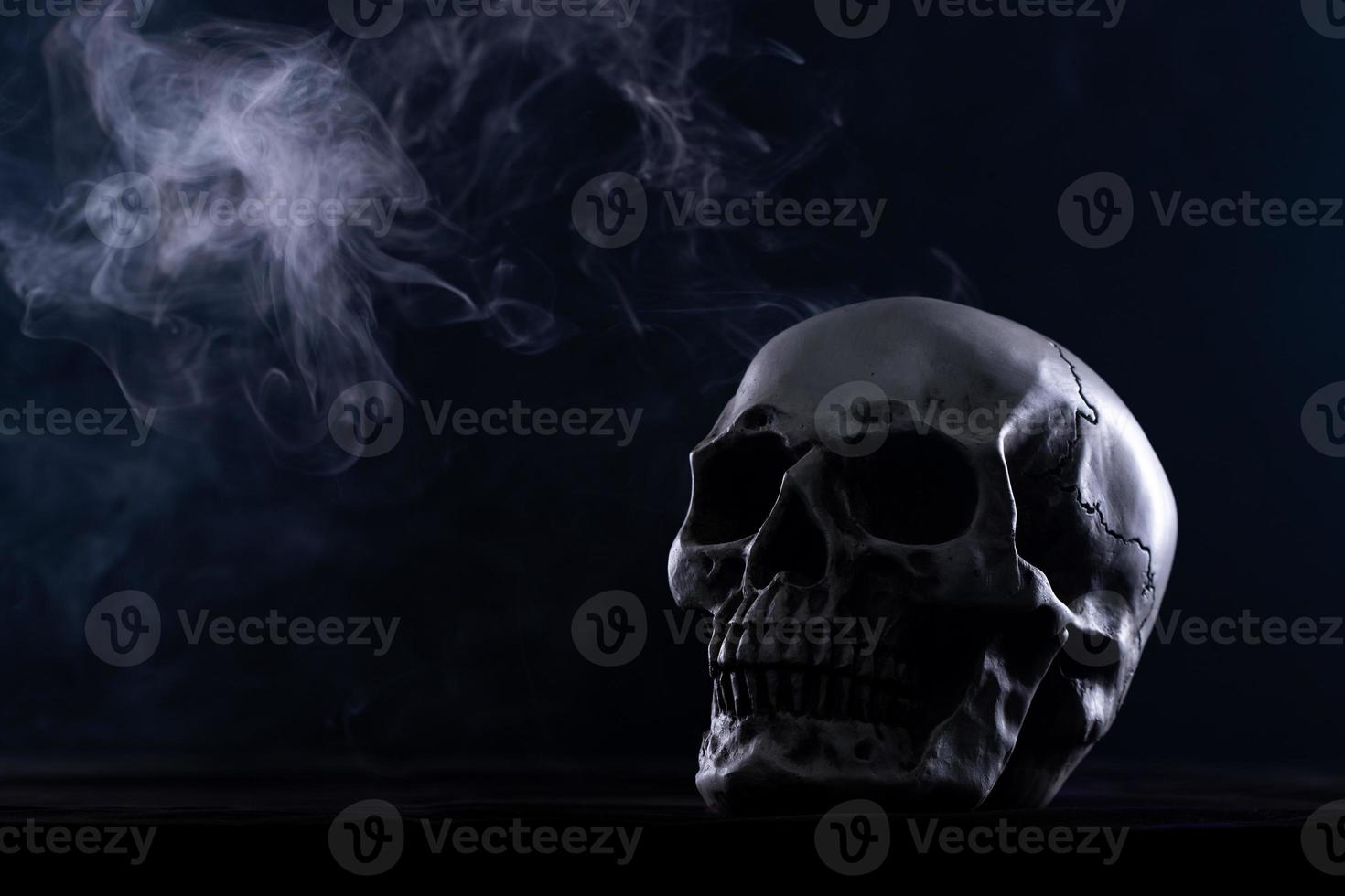 Halloween human skull on an old wooden table over black background. Shape of skull bone for Death head on halloween festival which show horror evil tooth fear and scary with fog smoke, copy space photo