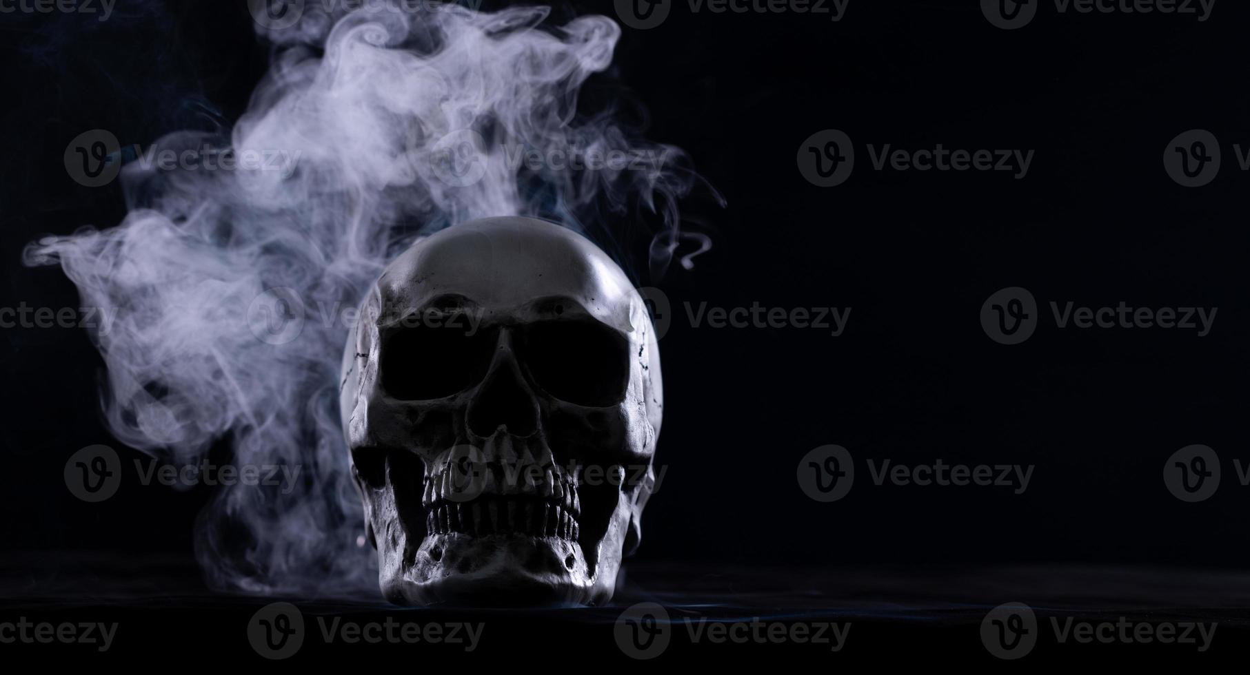 Halloween human skull on an old wooden table over black background. Shape of skull bone for Death head on halloween festival which show horror evil tooth fear and scary with fog smoke, copy space photo