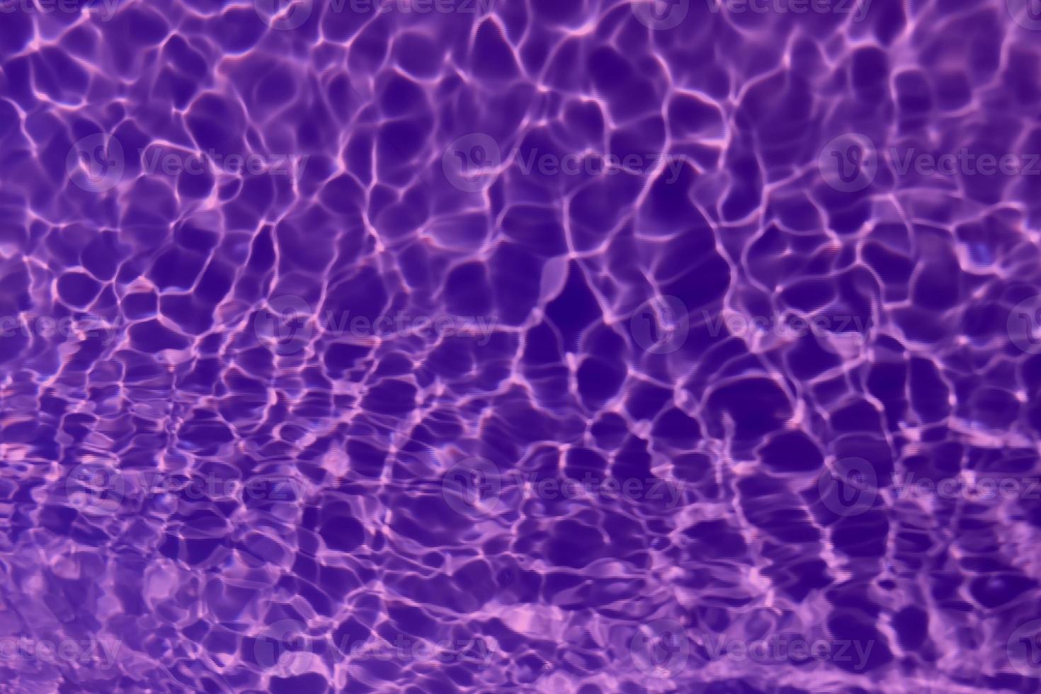 Defocus blurred transparent purple colored clear calm water surface texture with splash, bubble. Shining purple water ripple background. Surface of water in swimming pool. Tropical purple water color. photo