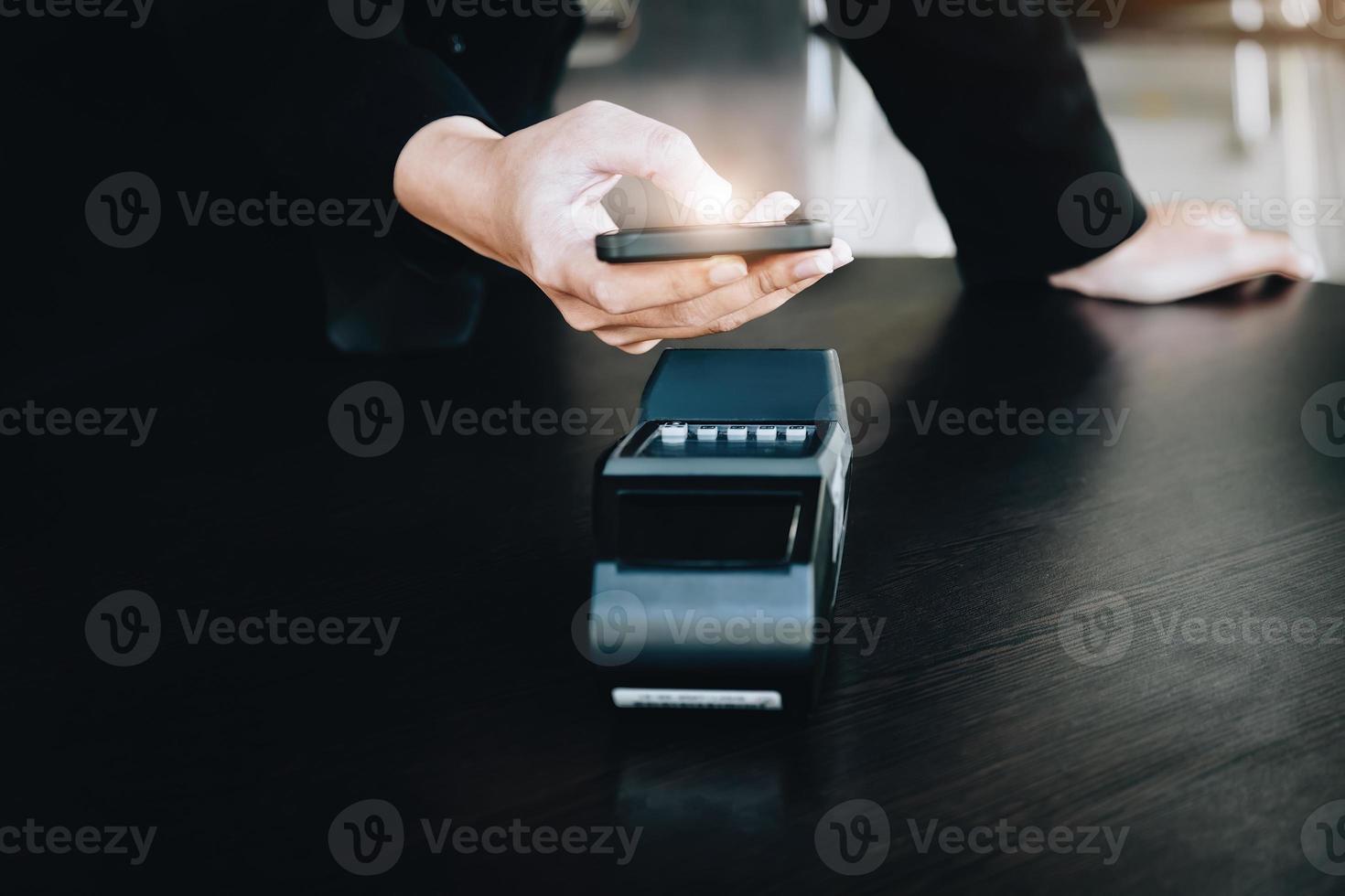Secure payment technology concept and service charge, customers are using their phone to pay using paywave technology by tapping near the electronic card terminal. photo