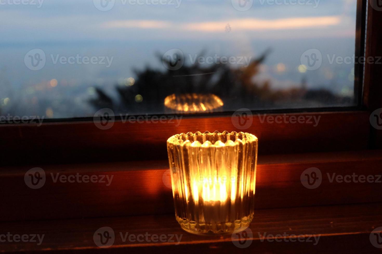 light candle near the window with scenery view. For use as wallpaper or background with copy space. Winter, new year, Christmas, winter, hugge, holiday concept. photo