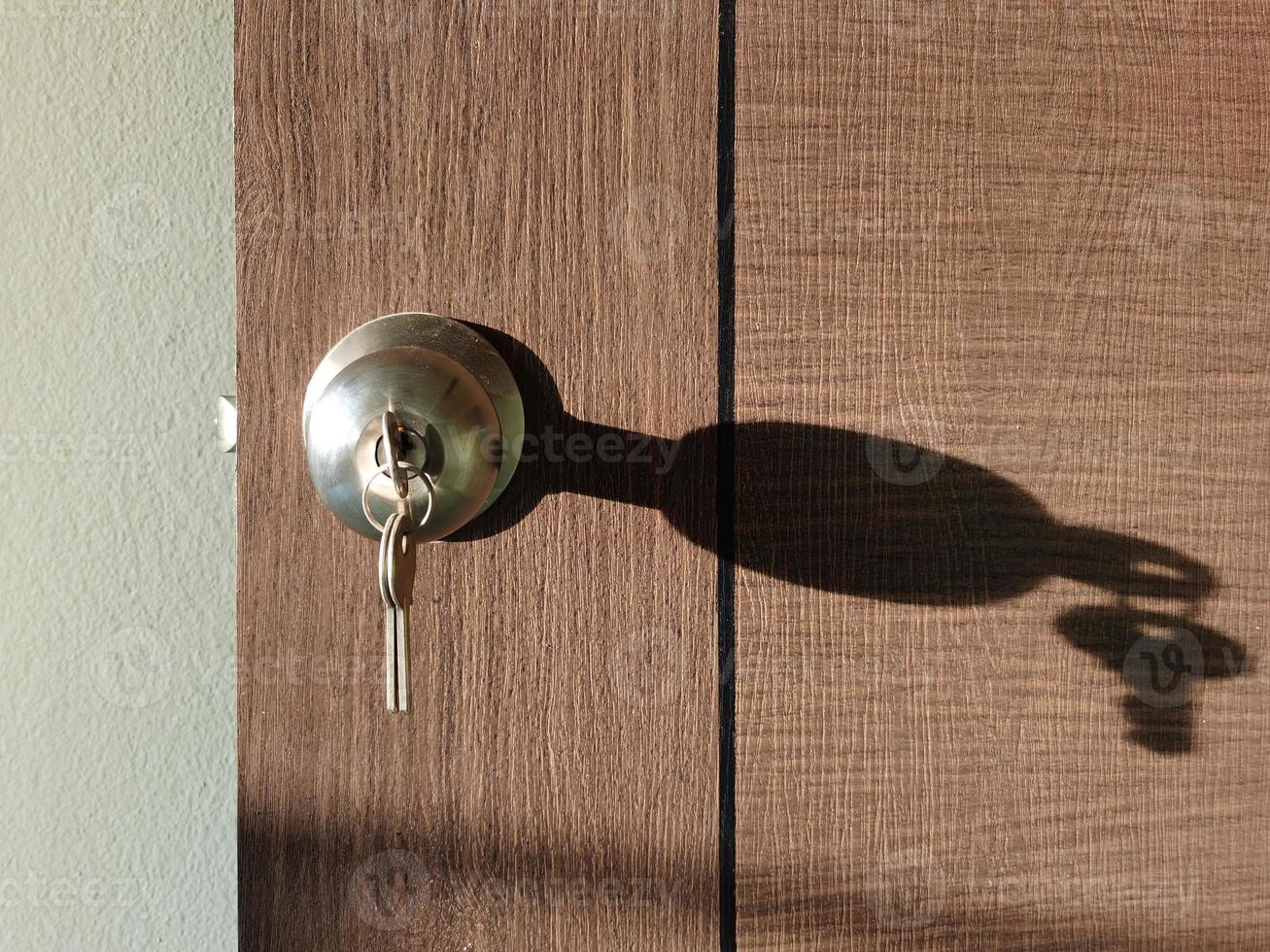 House key with home keyring in keyhole on wood door photo