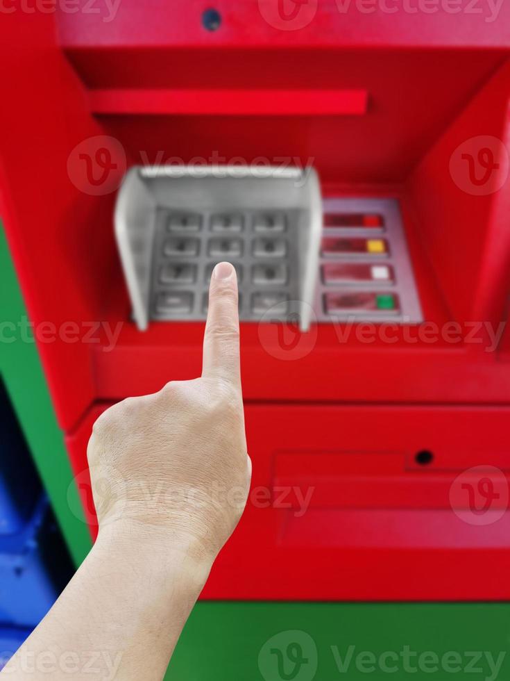 Man's hand about to enter code on ATM's numeric keypad, blurry. photo