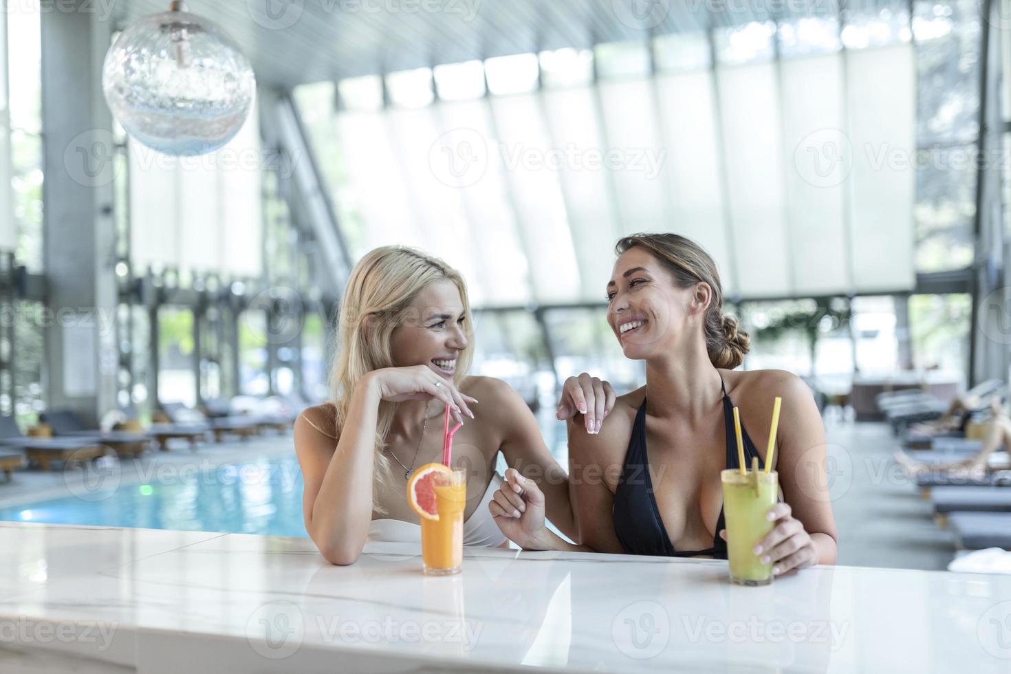 Women friends drink, cocktail mojito on pool bar, wear bikini luxury hotel near beach on tropical island relax photo