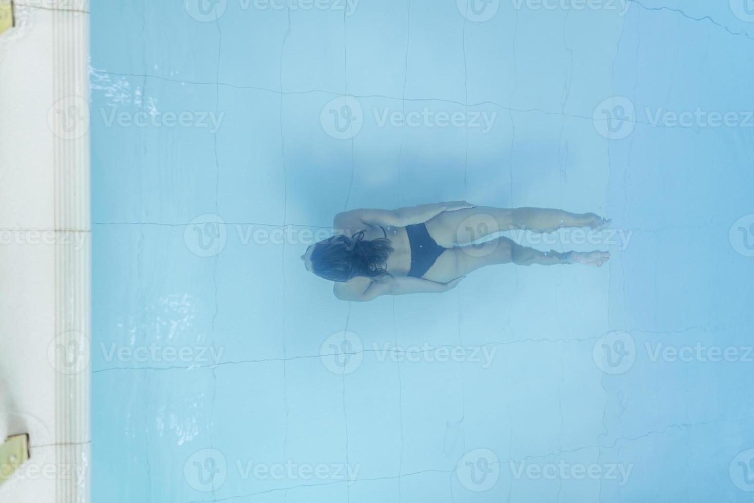 vista de drones sobre una joven buceando en una piscina azul foto