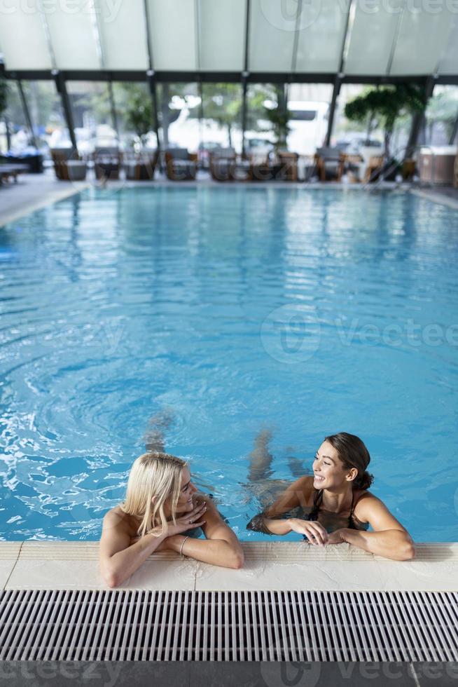 las amigas beben, cóctel mojito en el bar de la piscina, usan bikini hotel de lujo cerca de la playa en una isla tropical relajarse. hermosas mujeres jóvenes divirtiéndose en la piscina, bebiendo cócteles, sonriendo. foto