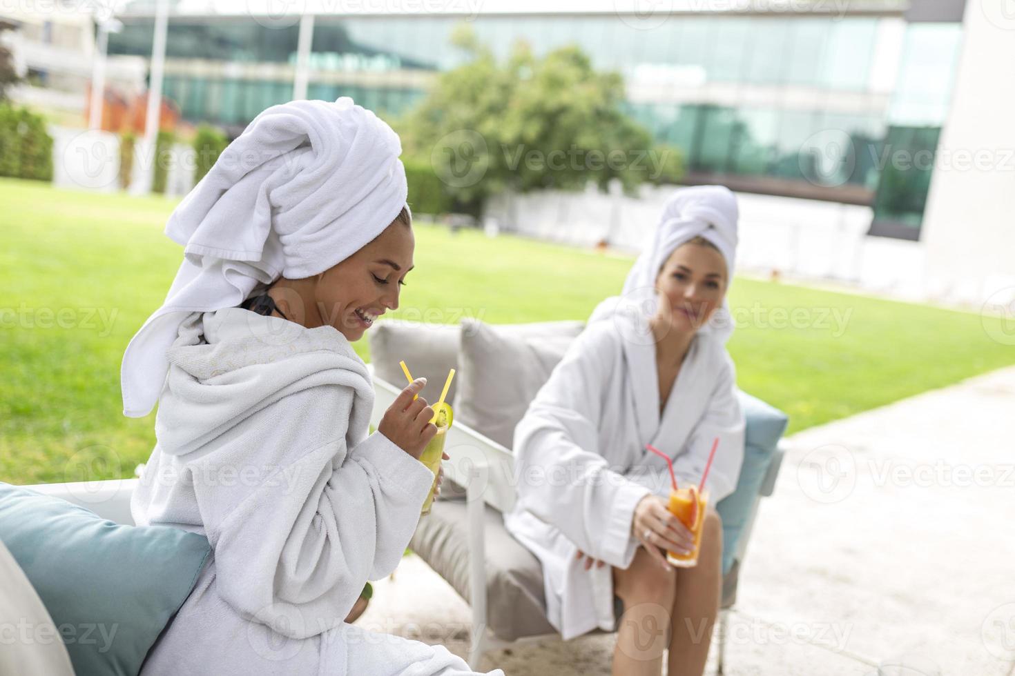Happy young beautiful women enjoying fun time after spa procedures together in luxury hotel, wearing towels on heads and bathrobes. photo