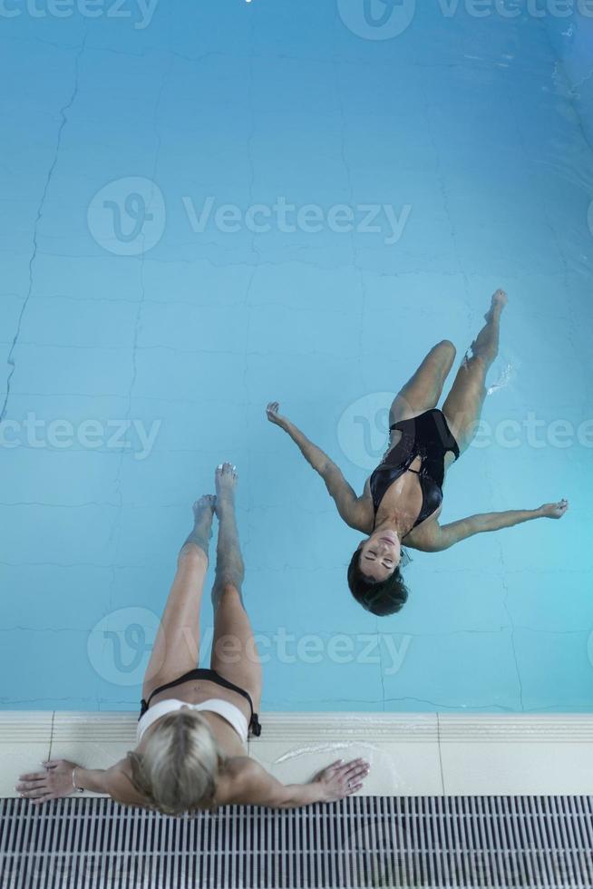 Rearview shot of two young women relaxing in the pool at a spa photo