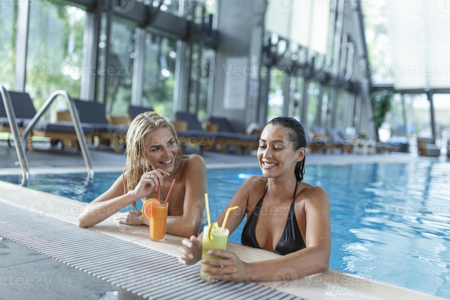 las amigas beben, cóctel mojito en el bar de la piscina, usan bikini hotel de lujo cerca de la playa en una isla tropical relajarse. hermosas mujeres jóvenes divirtiéndose en la piscina, bebiendo cócteles, sonriendo. foto