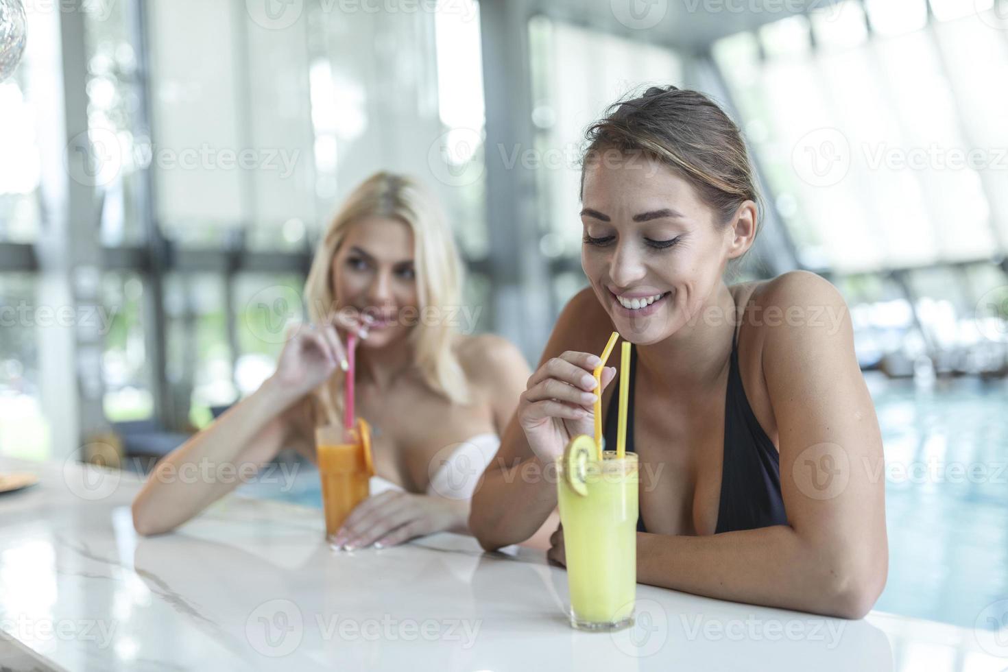 Two beautiful women relaxing in swimming pool with cocktails.pool bar at tropical tourist resort vacation destination photo