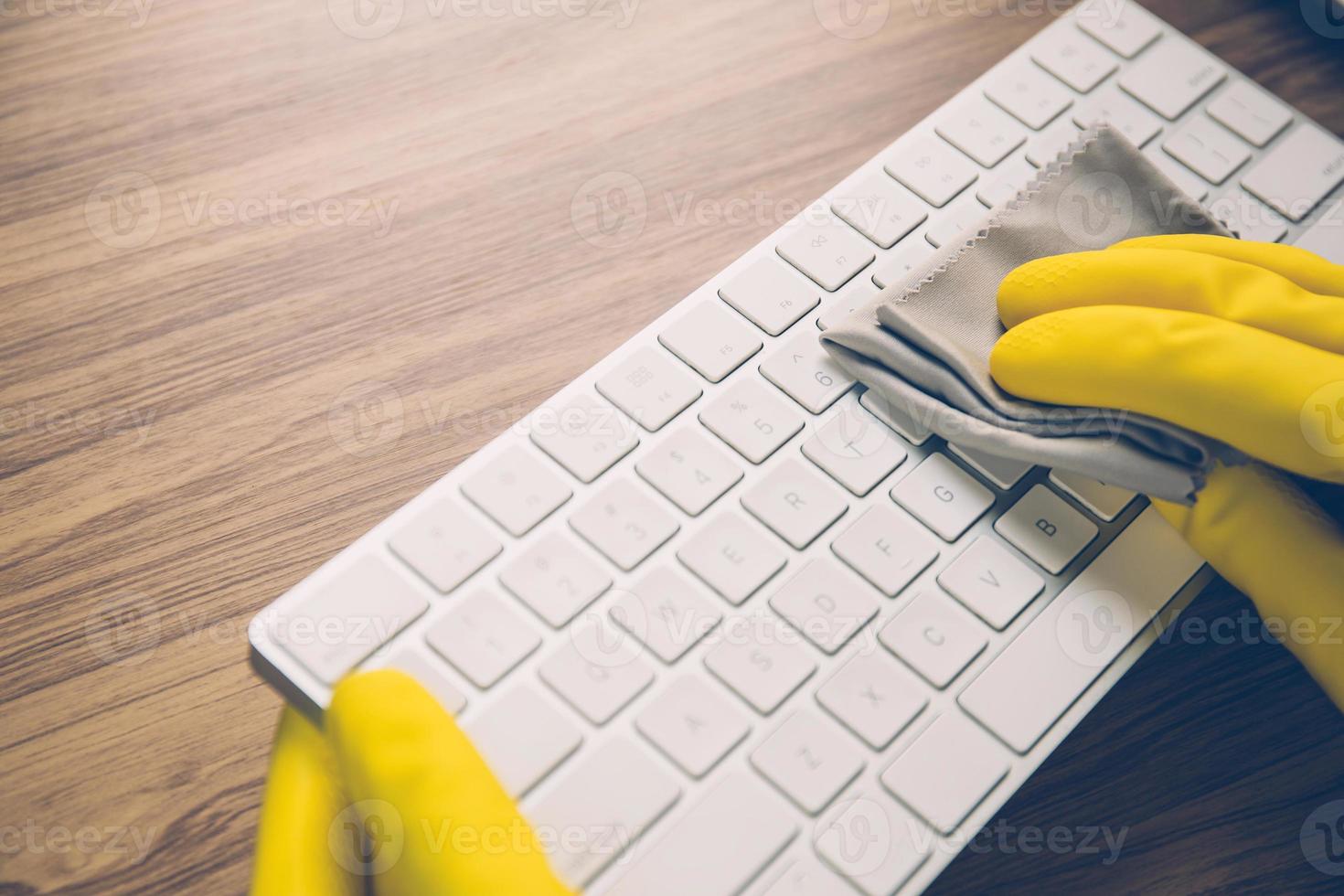 Hand of man cleaning keyboard computer with antibacterial for protect epidemic disease covid-19, fabric having antiseptic alcohol clean and wash laptop for on desk, business and health concept. photo