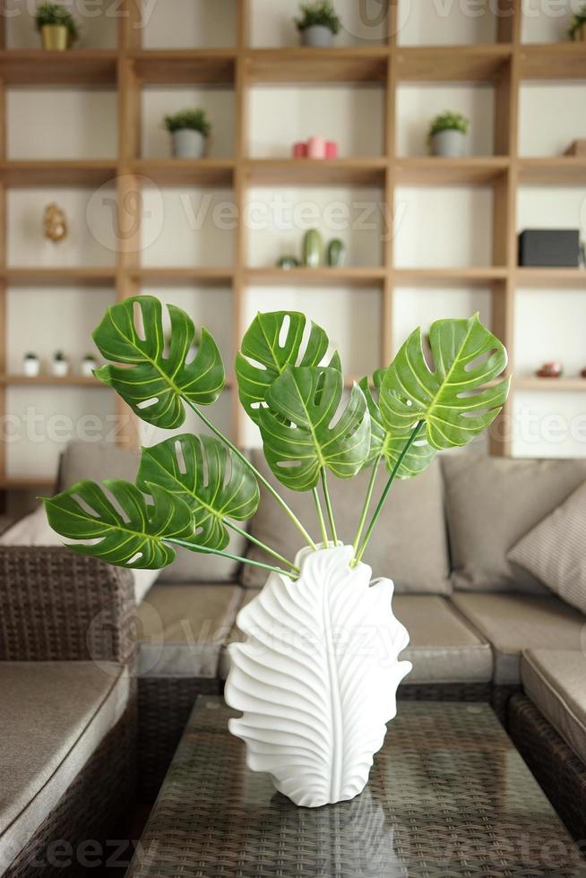 Monstera leaves standing in a white vase in a modern interior home photo