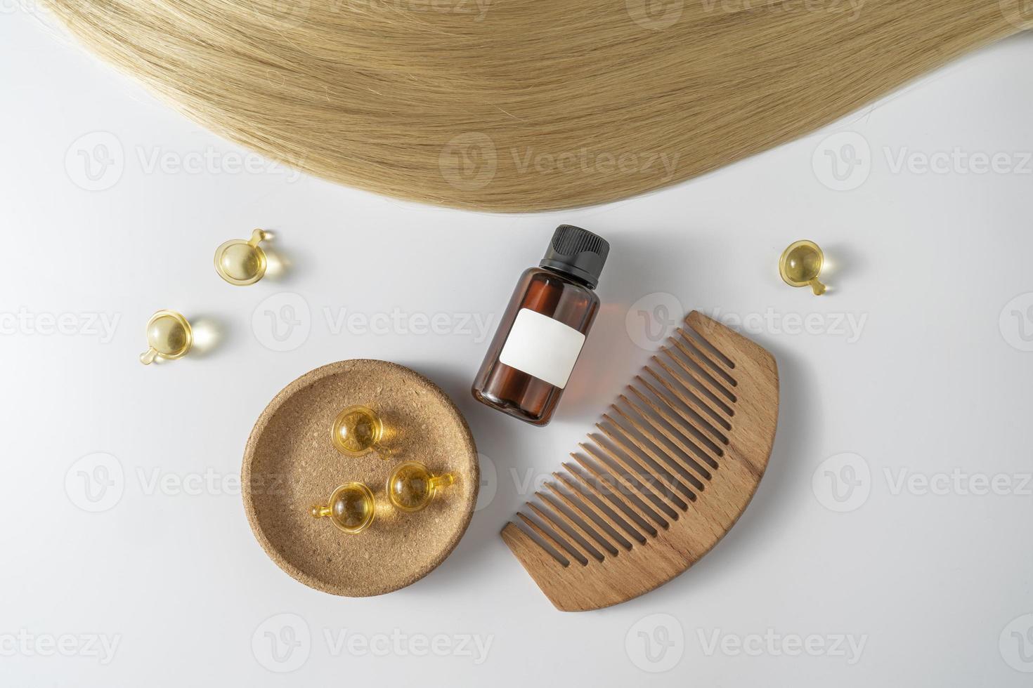 A hair care oil or serum in golden capsules lying on a strand of blond hair, product marketing mockup. A concept of hair care in a salon or at home photo