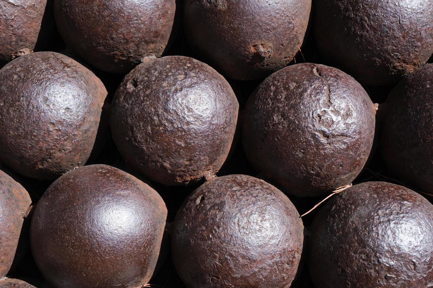 Antique rusty cannon balls, pattern, closeup, ancient iron cannonball in a sphere shape, texture, stack of round metal balls, war ammunition, background. photo