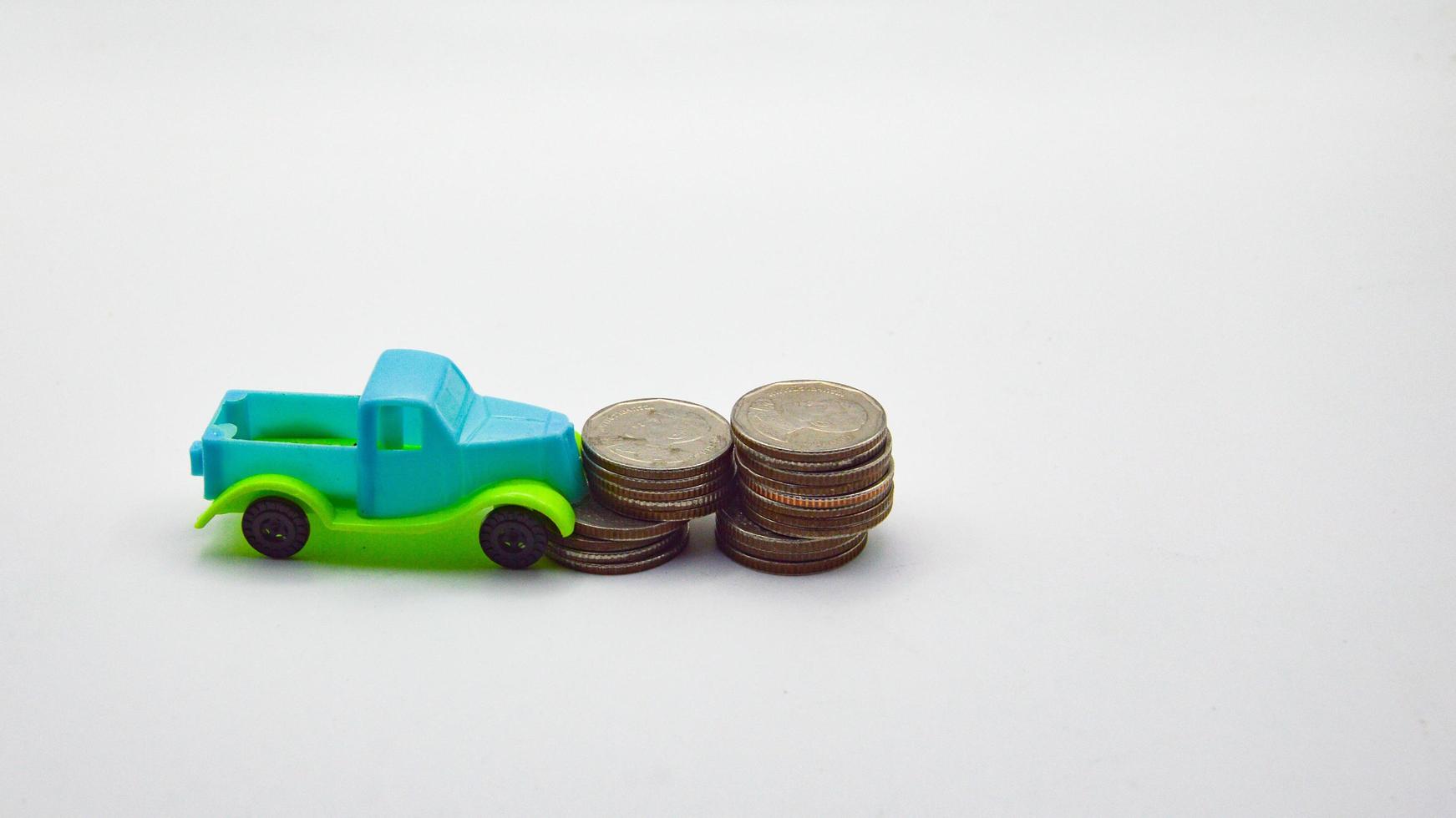 Blue-green pickup truck hit a pile of coins on a white background photo