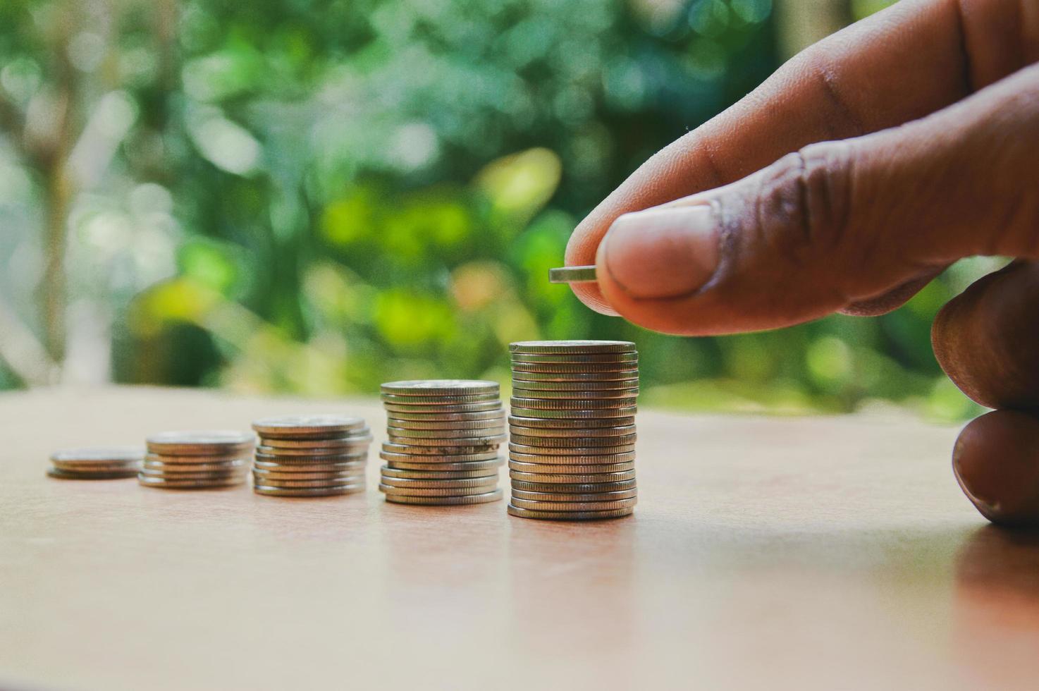 Coins stacked in a ladder with a man's hand putting coins on top. Concept, investment, retirement, savings. photo