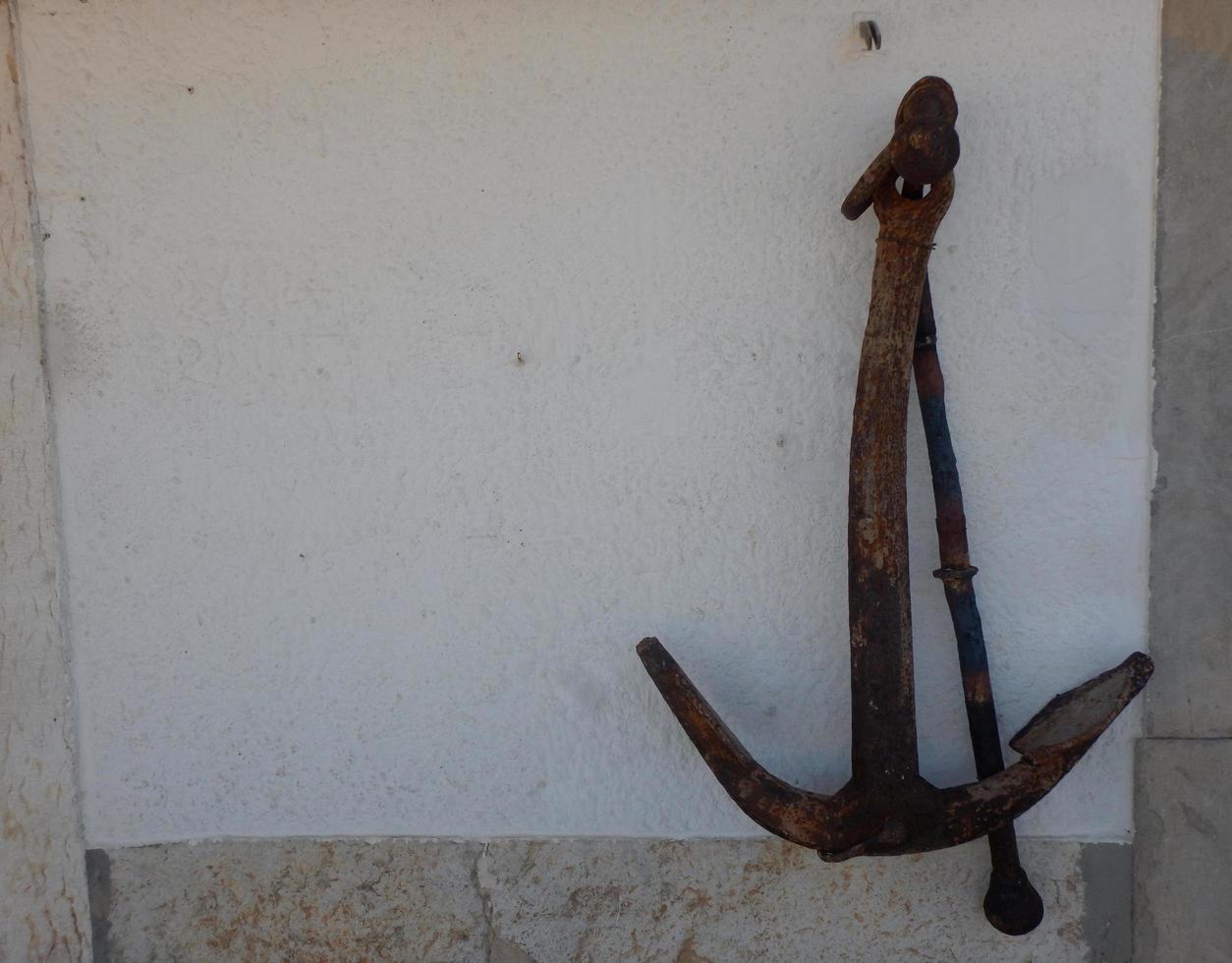 Old anchor on a white wall photo