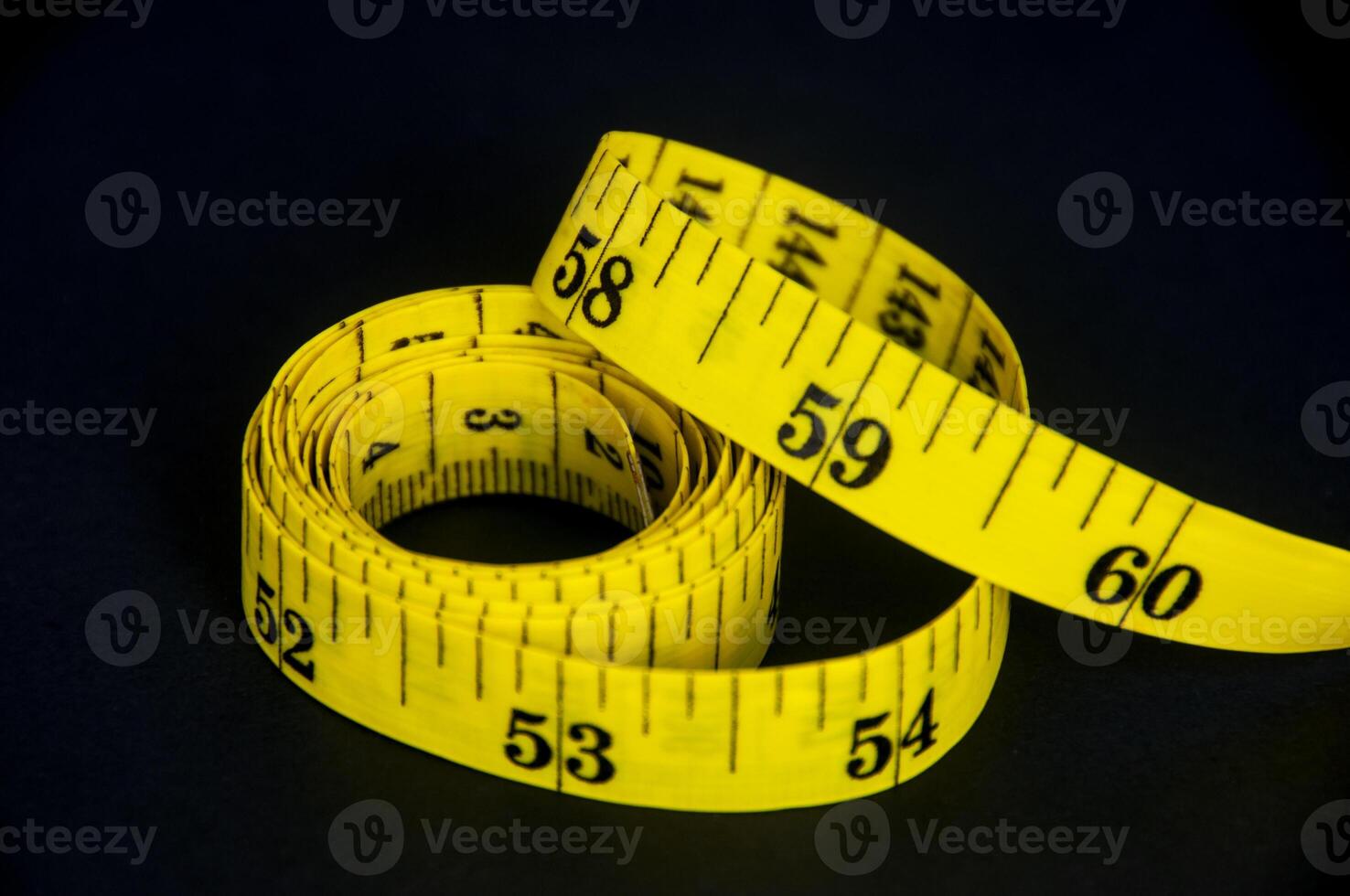 Measuring tape on dark background with customizable space for text. Copy space and weight loss concept photo