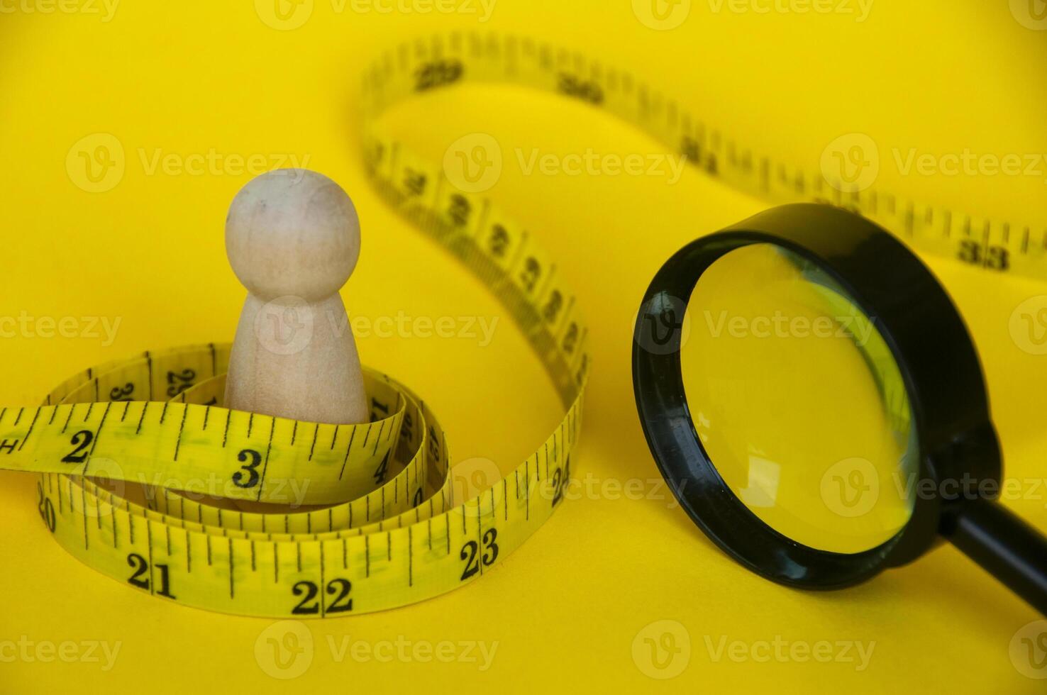 Wooden doll wrapped with yellow measuring tape with customizable space for text or ideas. Copy space and weight loss concept photo