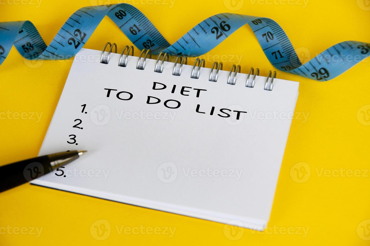 Diet to do list text on white notepad with blue measuring tape on yellow background. Health and diet concept photo