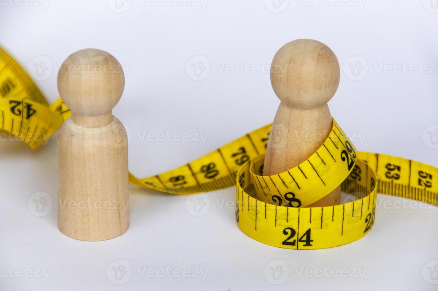 Wooden doll wrapped with yellow measuring tape with customizable space for text or ideas. Copy space and weight loss concept photo